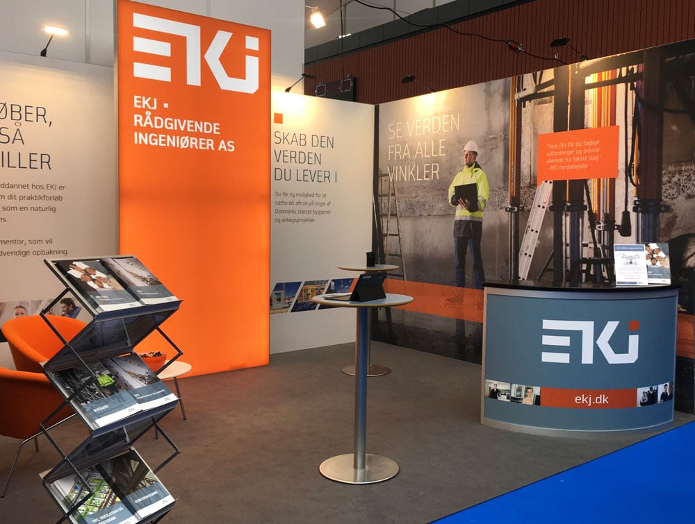 EKJ messestand med brochurestander, disk og stor grafik