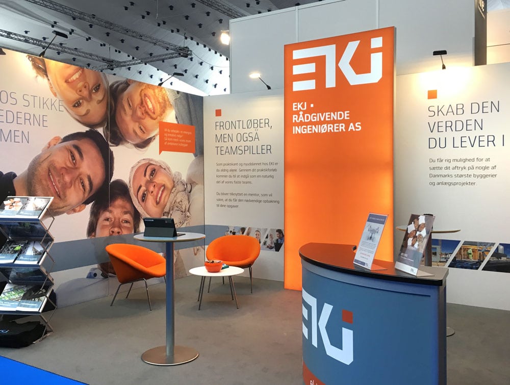EKJ messestand med orange profilvæg og mødeområde